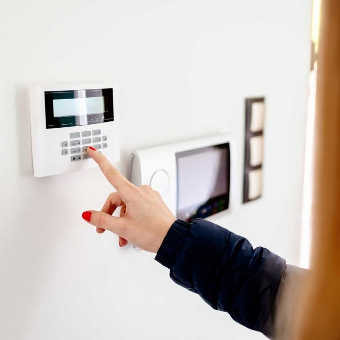 alarm Woman operating home security system installed by TEL Constructions